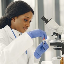 Medical doctor girl working with a microscope. Young female scientist doing vaccine research.